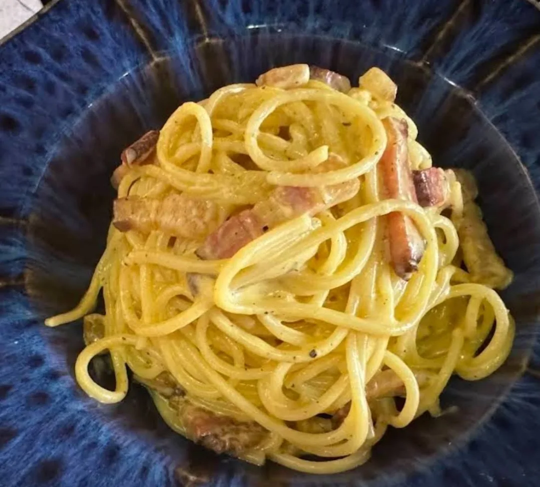 Spaghetti alla carbonara in a deep blue ceramic bowl