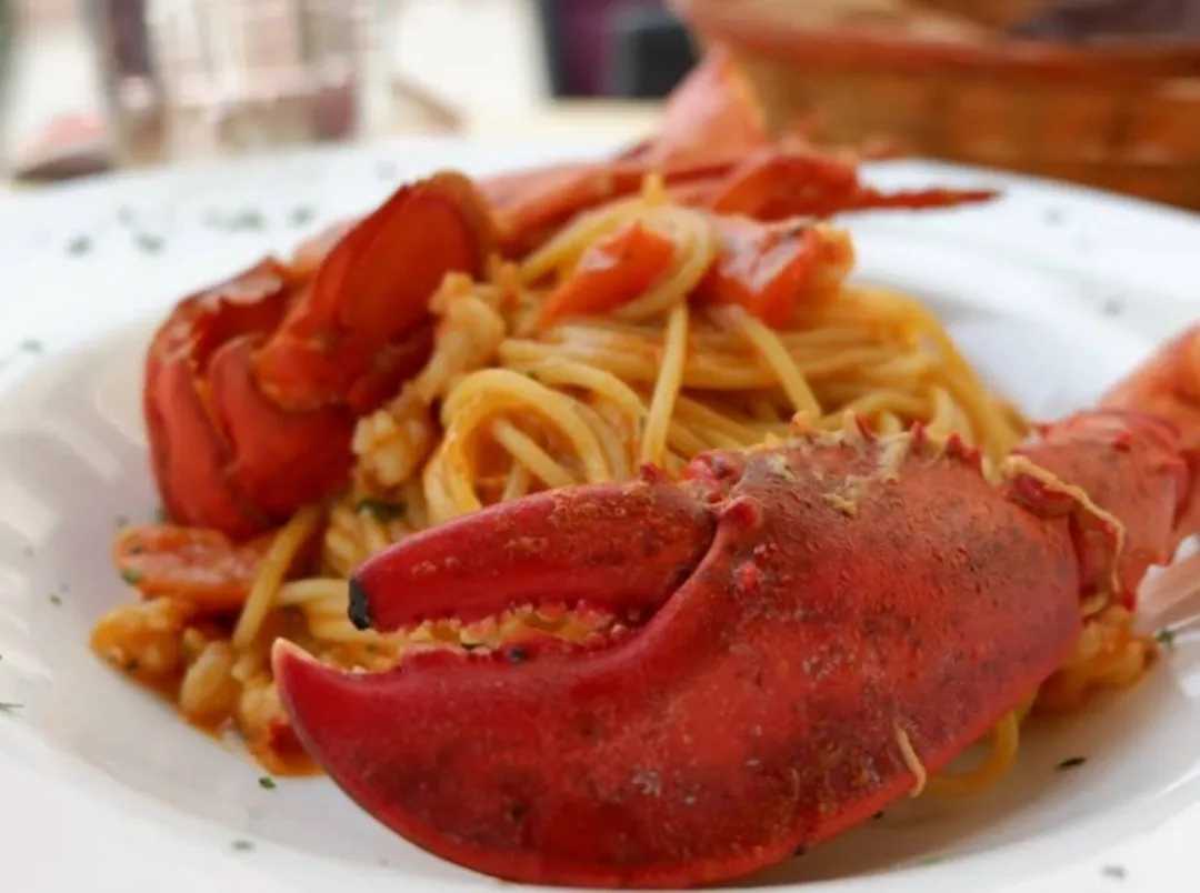 Spaghetti all'astice — lobster pasta with claws on a white plate