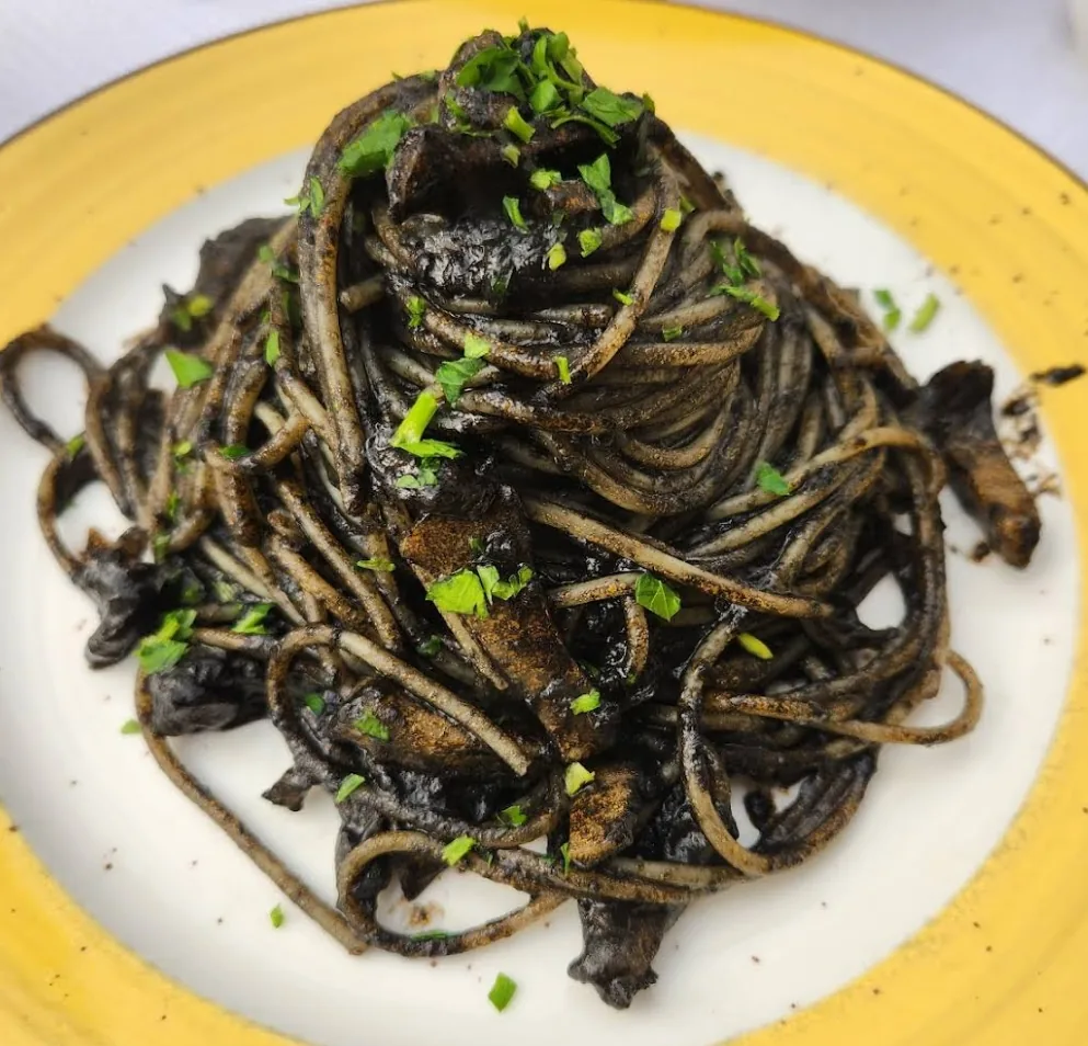 Spaghetti al nero di seppia served on a yellow plate