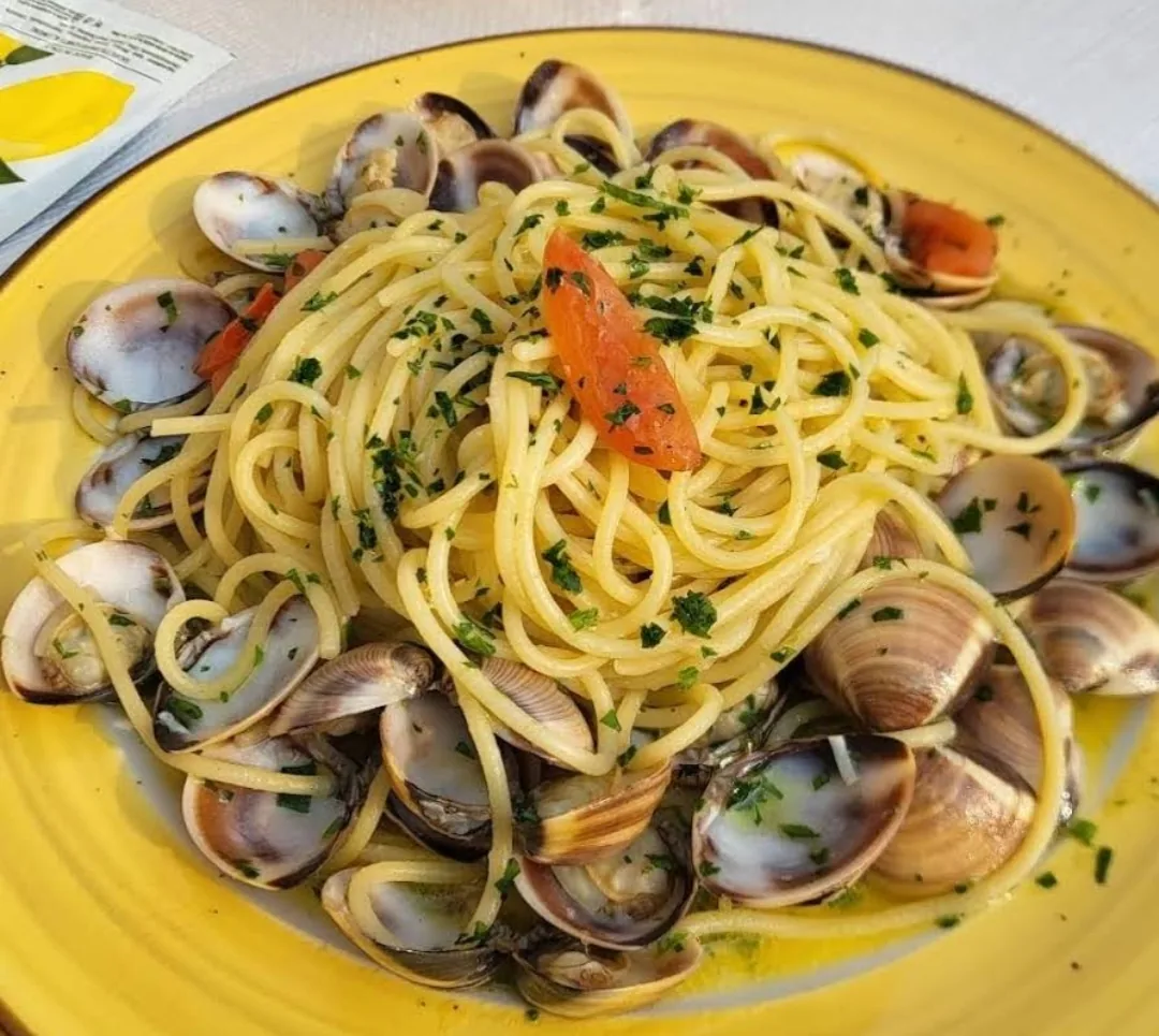 Spaghetti alle vongole on a hand-painted yellow Vietri plate